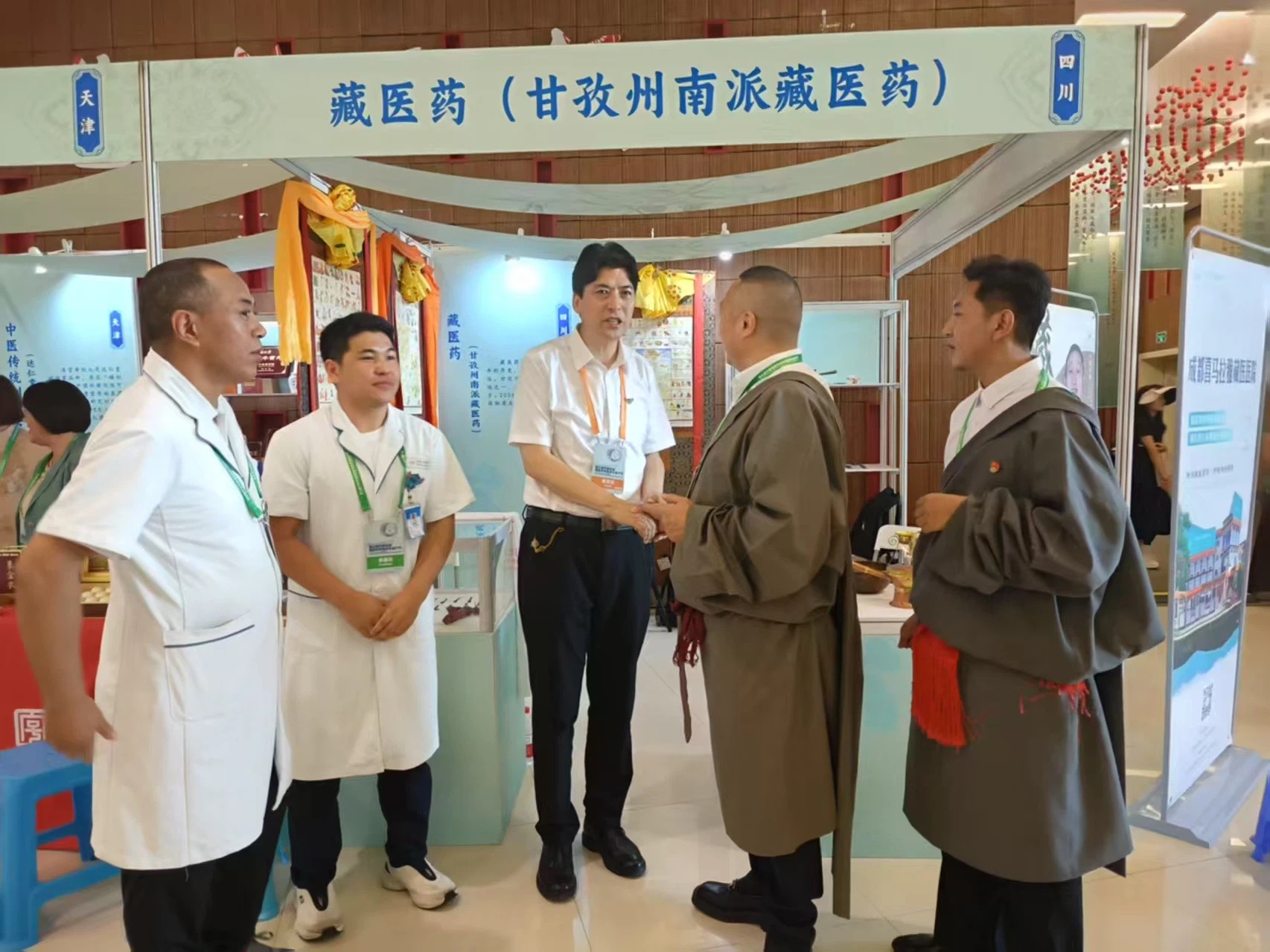 南派藏医药展位前，青佩院长与甘孜州文旅局领导握手交谈